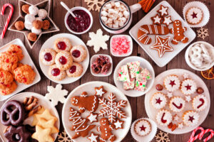 Plates of different holiday cookies on a wooden table.